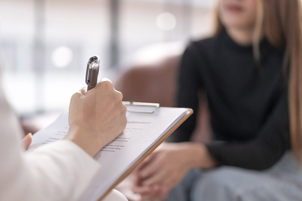a therapist makes notes on a clipboard while explaining IOP vs. PHP key differences and which is right for you.