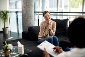 young woman seated on couch in an office setting with her addiciton treatment specialist discussing what to do after rehab and 8 tips for recovery