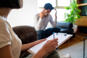 behavioral health specialist speaking with young man in an office setting about prescription drug addiction symptoms and how to recognize the signs of dependence