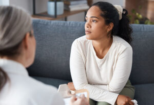 young woman seated in an a professional office with an older behavioral health specilst asking what is prescription drug addiction and understanding the impact of treatment options.