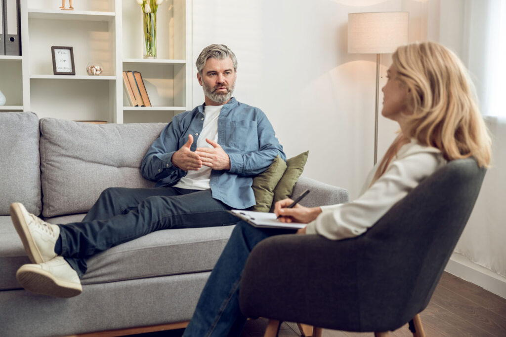 addiction therapist explaiining to male patient how counseling supports recovery from substance abuse